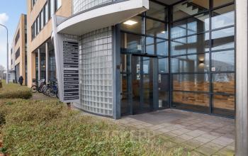 Moderne entree van een kantoorpand op Mollerusweg 84 in Haarlem Waarderpolder, met glazen gevel en fietsrekken. Ideaal voor wie kantoorruimte wil huren in een levendig gebied.