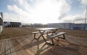 Exterieur van kantoorpand op Bingerweg 18A - 18R in Haarlem Waarderpolder met houten terras en picknicktafel, geschikt voor ontspannen pauzes tijdens kantooruren.