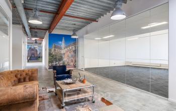 Industrieel kantoorpand te huur in Haarlem Waarderpolder aan de Bingerweg 18A - 18R met glazen wanden en een zithoek met banken en tapijt voor moderne werkruimte.