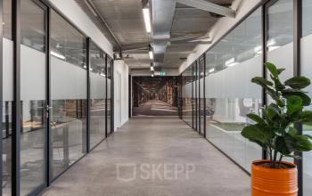 Moderne gang in kantoorpand aan Waarderweg 52 in Haarlem Waarderpolder met glazen wanden en een groene plant. Geschikt voor kantoorruimte huren in een zakelijke omgeving.