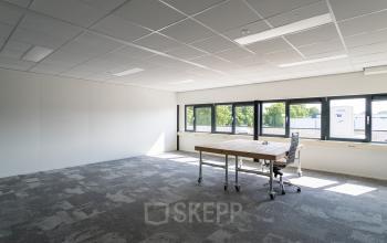 Licht kantoorpand op Waarderweg 52, Haarlem Waarderpolder met grote ramen, een bureau en een bureaustoel op tapijt. Ideale ruimte om kantoorruimte te huren.