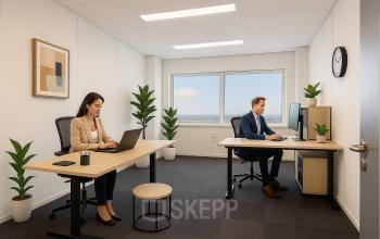 Moderne kantoorruimte huren in Haarlem Waarderpolder met twee personen bezig met laptopwerk. Het kantoorpand heeft een open, lichte uitstraling met stijlvol meubilair en groene planten voor extra sfeer.