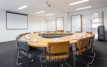 Vergaderzaal in kantoor op A. Hofmanweg 5A, Haarlem Waarderpolder, met halve ronde tafel, stoelen en projector, geschikt voor zakelijke meetings.