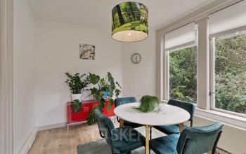 Kantoorruimte huren in Haarlem Zuid, locatie Florapark 7. Gezellige werkruimte met ronde tafel, comfortabele stoelen, planten en raam met uitzicht op groen.