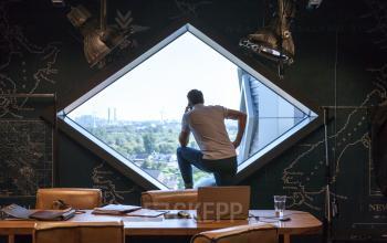 Modern ingerichte kantoorruimte in kantoorpand Suikersilo Oost-West Halfweg, met persoon kijkend uit raam in denkpose.