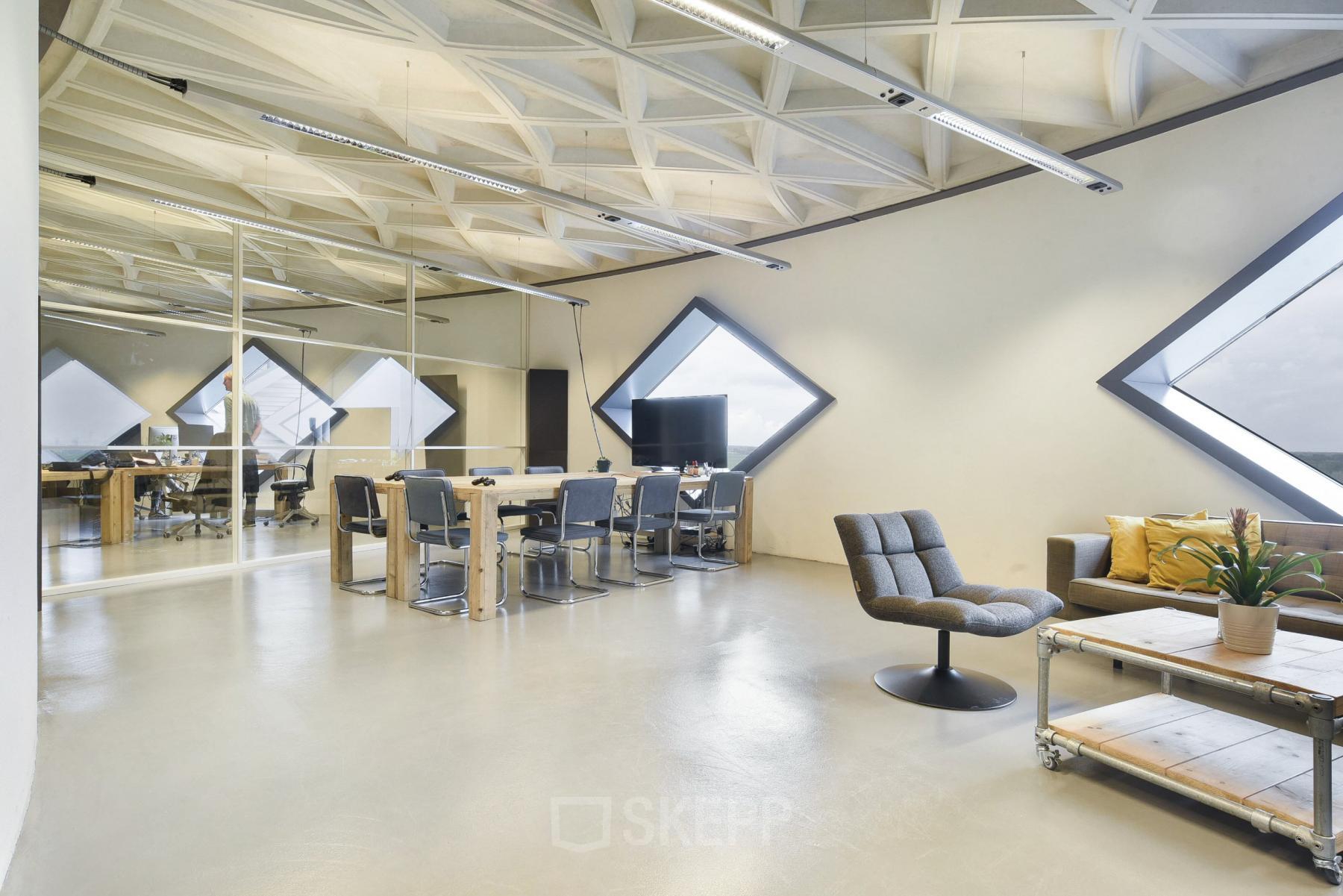 Modern ingerichte kantoorruimte in Suikersilo Oost-West 1-41 te Halfweg met grote ramen, een vergadertafel en comfortabele loungehoek.
