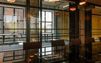 Een moderne vergaderruimte met glazen wanden in een kantoorpand op Haarlemmerstraatweg 13, Halfweg. De stijlvolle inrichting en verlichting creëren een ideale omgeving voor zakelijke bijeenkomsten. Overweeg deze kantoorruimte te huren.