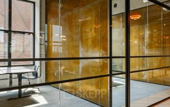 Modern kantoorpand met glazen wanden en houten accenten op Haarlemmerstraatweg 13, Halfweg. Licht interieur, ideaal voor kantoorruimte huren. Comfortabel ingericht met tafels en stoelen in een bull-pen lay-out.