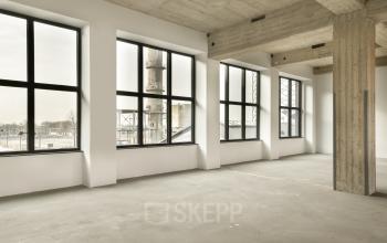 Ruime, lichte kantoorruimte in kantoorpand op Haarlemmerstraatweg 13A, Halfweg. Grote ramen bieden uitzicht op industriële omgeving.