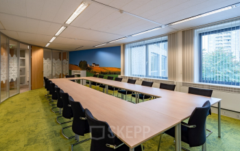 Vergaderruimte in kantoorpand Geerstraat 115, Heerlen, met een grote U-vormige tafel, comfortabele stoelen en veel natuurlijk licht. Ideaal voor bedrijven die kantoorruimte huren.