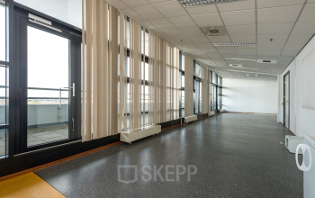 Ruime, goed verlichte kantoorruimte in kantoorpand Heerlen met grote ramen en grijze vloeren, perfect voor bedrijven die kantoorruimte willen huren.