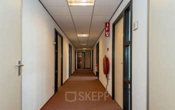 Kantoorruimte huren in Heerlen met lange hal met meerdere deuren, goed verlicht en onderhoudsvriendelijk. Geschikt voor bedrijven die flexibiliteit en functionaliteit zoeken.