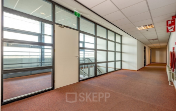 Ruime gang in het kantoorpand op Milaanstraat 70-110, Heerlen met grote ramen en heldere verlichting. Ideaal voor bedrijven die kantoorruimte huren en een professioneel werkklimaat zoeken.