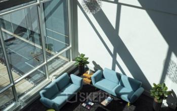Interieur kantoorruimte op Snellius 1, Heerlen met moderne zitbanken en gele stoelen in een lichte lounge.