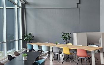 Moderne, gemeubileerde kantoorruimte in Snellius 1, Heerlen, met houten vloer, grote ramen en kleurrijke stoelen rondom werktafels. Kantoorruimte huren in een eigentijds kantoorpand.