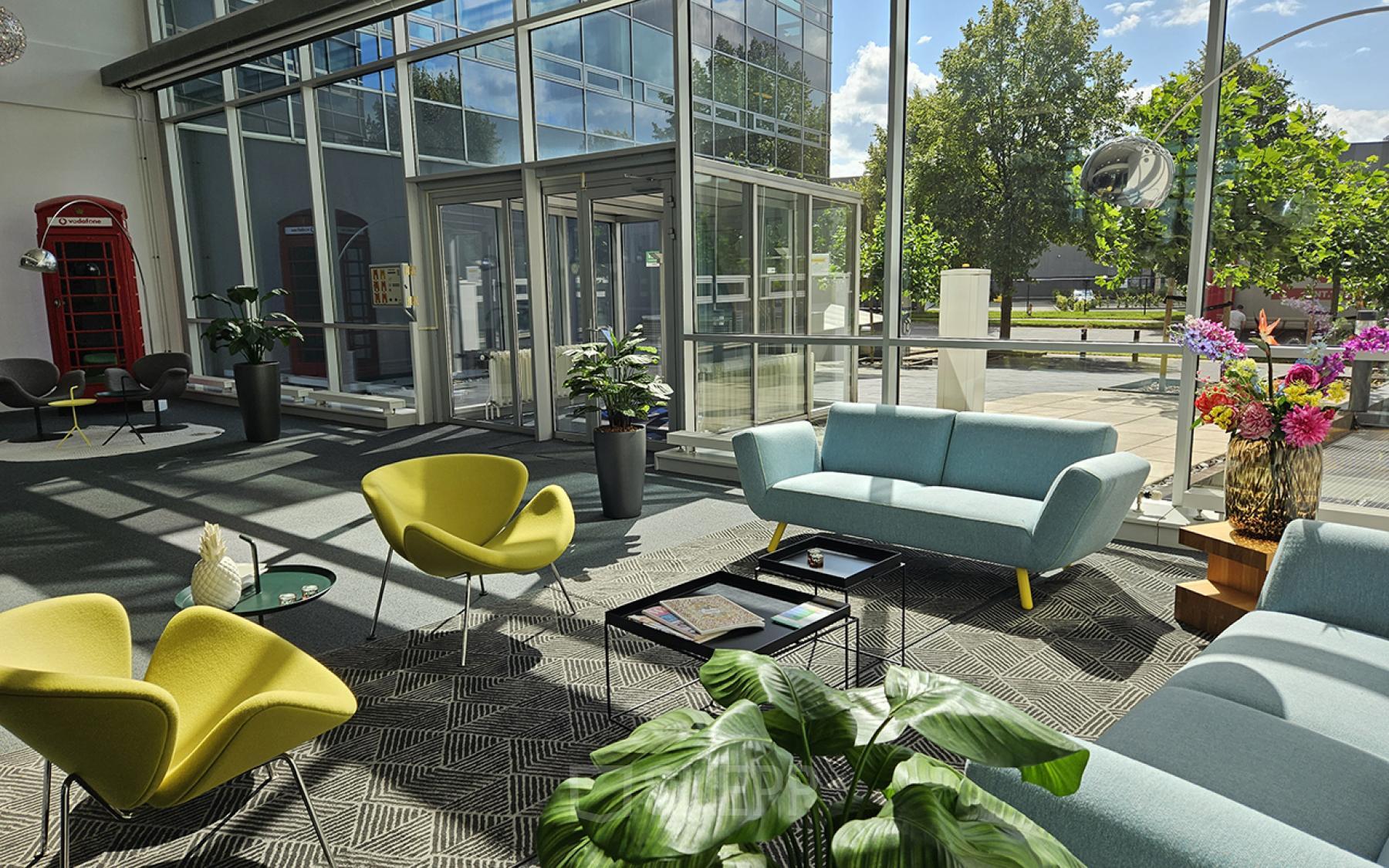 Moderne en lichte lounge bij Snellius 1 in Heerlen met comfortabele zitplaatsen en veel natuurlijke lichtinval door grote ramen, ideaal voor informele bijeenkomsten.
