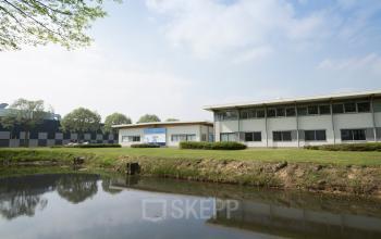 Exterieur van kantoorpand aan de Steenovenweg 5 in Helmond, met uitzicht op een buitenruimte met waterpartijen.