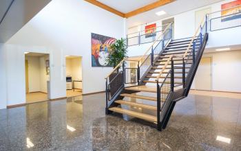 Ruim en modern interieur van het kantoorpand op Steenovenweg 5, Helmond. Glanzende vloeren, kunst aan de muren, en een centrale trap. Kantoorruimte huren in een nette omgeving.