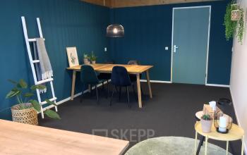 Kantoorruimte huren op Steenovenweg 5 in Helmond met een vergadertafel, stoelen, decoratieve planten, en een groene muur.