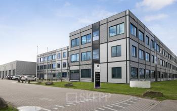 Buitenzijde van het kantoorpand op Jan Tinbergenstraat 202 in Hengelo, met moderne uitstraling en ruime parkeerplaats. Geschikt voor bedrijven die kantoorruimte willen huren.