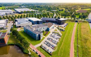 Luchtfoto van het kantoorpand aan de Jan Tinbergenstraat 202 in Hengelo, omringd door groen en parkeerplaatsen. Ideale locatie voor kantoorruimte huren.