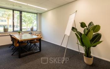 Kantoorruimte huren op Jan Tinbergenstraat 202, Hengelo: een helder kantoor met grote ramen, houten tafel, stoelen en planten. Ideaal voor creatieve en productieve momenten.
