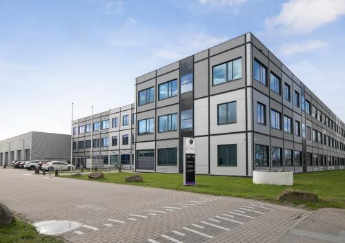 Buitenzijde van het kantoorpand op Jan Tinbergenstraat 202 in Hengelo, met moderne uitstraling en ruime parkeerplaats. Geschikt voor bedrijven die kantoorruimte willen huren.