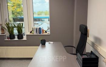Kantoorruimte huren op Hamerstraat 10, Hengelo. Een strak ingerichte ruimte met bureaus, een comfortabele stoel en uitzicht op de buitenomgeving.