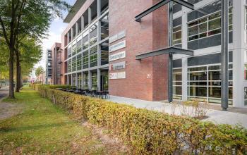 Buitenzijde van het kantoorpand gelegen aan Demmersweg 21 - 37, Hengelo, met goed onderhouden gevel en groene omgeving.