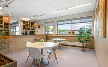 Kantoorruimte huren op Hazenweg 2-2, Hengelo: moderne kantine met eettafels, stoelen en kunstwerken aan de muur.