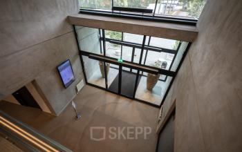 Entree van het kantoorpand aan Lintelerweg 40 in Hengelo met een uitzicht op glazen deuren en een moderne binnenruimte.