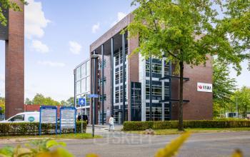 Modern kantoorpand op Demmersweg 41-47, Hengelo met meerdere verdiepingen en grote ramen, omgeven door groen.
