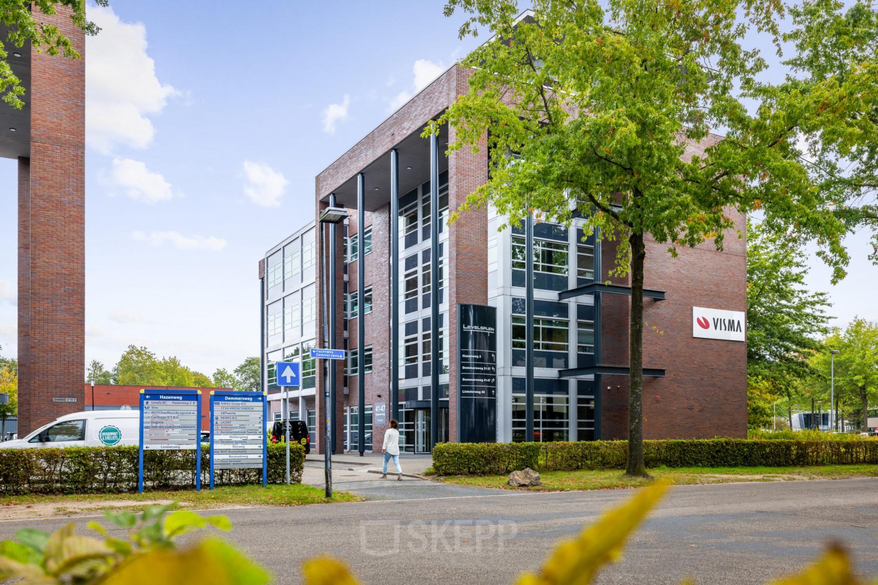 Modern kantoorpand op Demmersweg 41-47, Hengelo met meerdere verdiepingen en grote ramen, omgeven door groen.