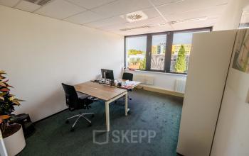 Lichte kantoorruimte te huur op Welbergweg 60, Hengelo met twee bureaus, comfortabele stoelen en groot raam voor natuurlijk licht.