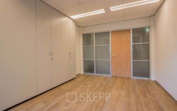 Onverharde kantoorruimte op Mozartlaan 25, Hilversum, met houten vloer en inbouwkasten, ideaal voor wie een kantoorpand wil huren. Geen meubilair aanwezig, klaar voor eigen inrichting.