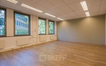 Lichte en ruime kantoorruimte te huur op Mozartlaan 25, Hilversum, met grote ramen en houten vloer, ideaal voor een open werkruimte.