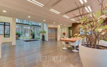 Ingang van het kantoorpand op Catharina van Renneslaan 20, Hilversum, met moderne receptiemeubels en verlichting. Geschikt voor kantoorruimte huren.