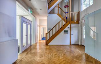 Lichte entree van kantoorpand Utrechtseweg 47 Hilversum, met houten vloer en trap. Ideale plek voor kantoorruimte huren met ruime doorgangen en moderne afscheiding.