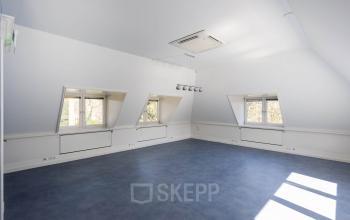 Lichte kantoorruimte op Utrechtseweg 47 in Hilversum, zonder interieurmeubels, met drie ramen en blauw vloeroppervlak. Ideaal voor wie kantoren wil huren met frisse uitstraling en veel natuurlijk licht.