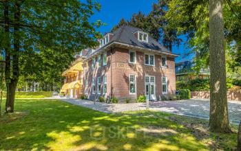Historisch kantoorpand op Utrechtseweg 47 in Hilversum omgeven door groen.
