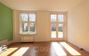 Kantoorpand aan de Utrechtseweg 47 in Hilversum met grote ramen die natuurlijk licht binnenlaten en een houten vloer.