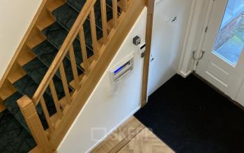 Entree van een kantoorpand aan de Utrechtseweg 47 in Hilversum met houten trap en inkomhal, geschikt voor bedrijven die kantoorruimte willen huren.