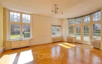 Lichte ruimte in een kantoorpand op Utrechtseweg 47, Hilversum met houten vloer en grote ramen. Ideaal voor kantoorruimte huren met uitzicht op groene omgeving.