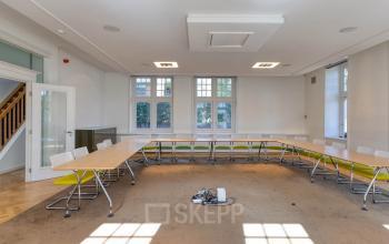 Kantoorruimte huren in Hilversum met een lichte vergaderruimte, voorzien van tafels, stoelen en een tapijtvloer. Ideaal voor zakelijke bijeenkomsten.