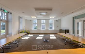 Kantoorpand aan de Utrechtseweg 47, Hilversum met lichte vergaderruimte en hoekige ramen. Tafels zijn U-vormig neergezet, geschikt voor zakelijke bijeenkomsten. Geschikt voor bedrijven die kantoorruimte willen huren.