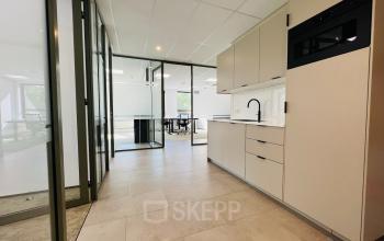 Strakke kantoorruimte te huur in Hilversum met moderne keukenfaciliteiten en glazen scheidingswanden voor een open en lichte uitstraling.