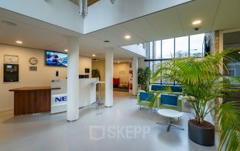 De entree van het kantoorpand op Olympia 4 in Hilversum, voorzien van een ruime lobby met zitplaatsen en een receptiebalie. Ideaal voor wie kantoorruimte wil huren in een moderne omgeving.