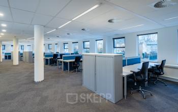 Kantoorruimte huren in Hilversum op Olympia 4, met ruime open vloerindeling, grote ramen en meerdere bureaus met bureaustoelen, geschikt voor diverse werkactiviteiten.