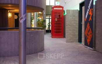 Binnenkant van kantoorpand op Catharina van Renneslaan 8-10, Hilversum, met een rode telefooncel als decoratief element en moderne betonnen elementen. Ideaal voor kantoorruimte huren.