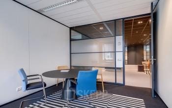 Kantoorruimte in Hoevelaken aan De Wel 20, voorzien van vergadertafel en stoelen, rustig verlicht en ideaal voor zakelijke bijeenkomsten. Geschikt voor huur als moderne werkplek.